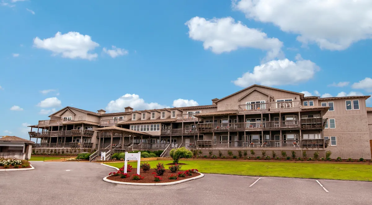 An exterior view of the property showcasing balconies with cozy seating and lush landscaped gardens. The scene suggests a quiet retreat, ideal for relaxing and enjoying ocean breezes or sunset views from the comfort of a private balcony.